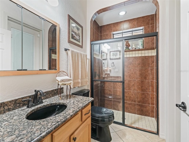 bathroom featuring vanity, tile patterned flooring, a shower with door, and toilet