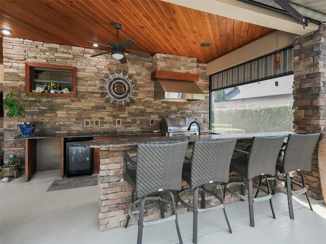 view of patio featuring ceiling fan, beverage cooler, exterior kitchen, and an outdoor bar