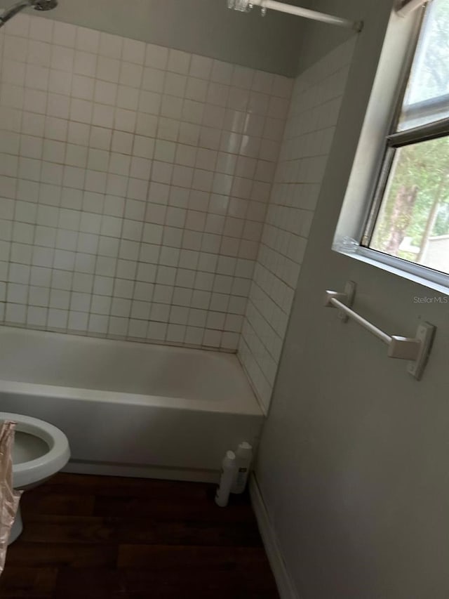 bathroom featuring hardwood / wood-style floors, tiled shower / bath combo, and toilet