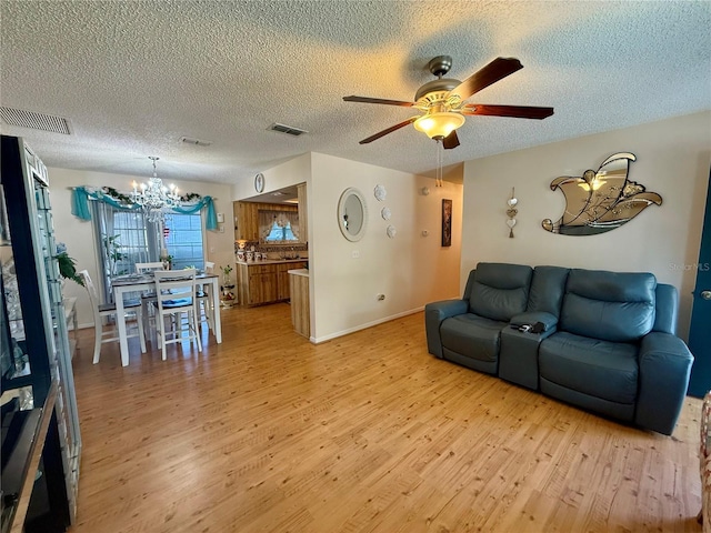 living room with visible vents, light wood finished floors, and ceiling fan with notable chandelier