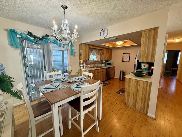 dining room featuring an inviting chandelier, light wood-style flooring, and a textured ceiling