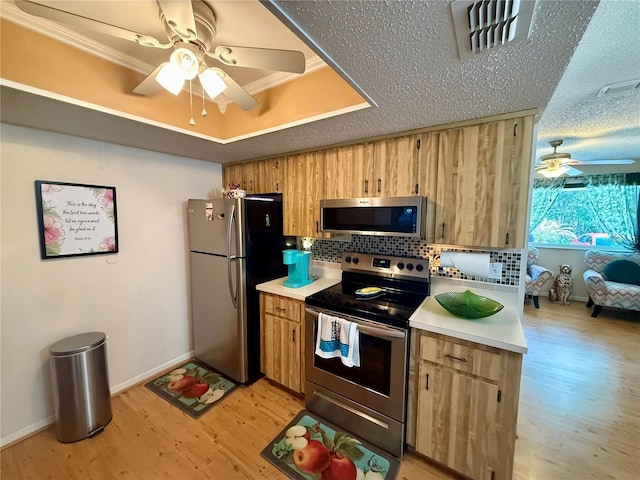 kitchen featuring visible vents, a raised ceiling, appliances with stainless steel finishes, light countertops, and light wood-type flooring