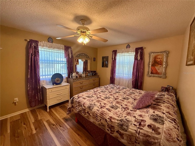 bedroom with baseboards, a textured ceiling, a ceiling fan, and wood finished floors