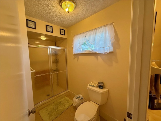 bathroom with a stall shower, a textured ceiling, and toilet