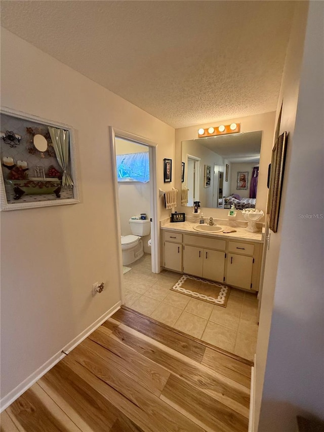 bathroom featuring a textured ceiling, vanity, wood finished floors, and toilet