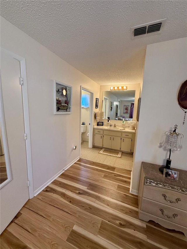 full bath featuring visible vents, toilet, wood finished floors, a textured ceiling, and vanity