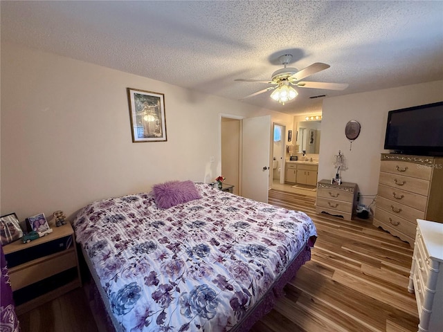 bedroom featuring visible vents, connected bathroom, ceiling fan, a textured ceiling, and wood finished floors