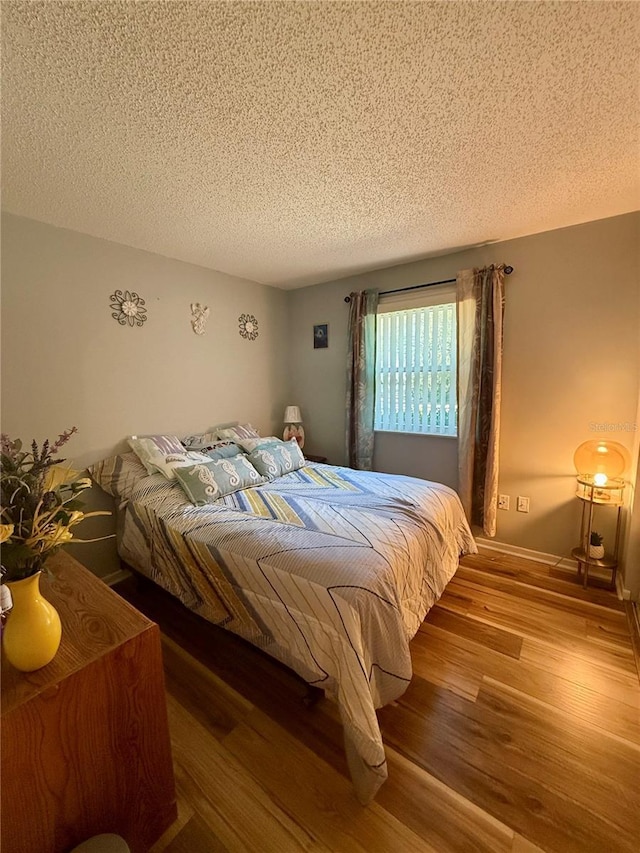 bedroom with a textured ceiling and wood finished floors