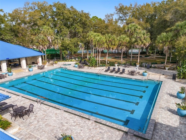 community pool with a patio area and fence