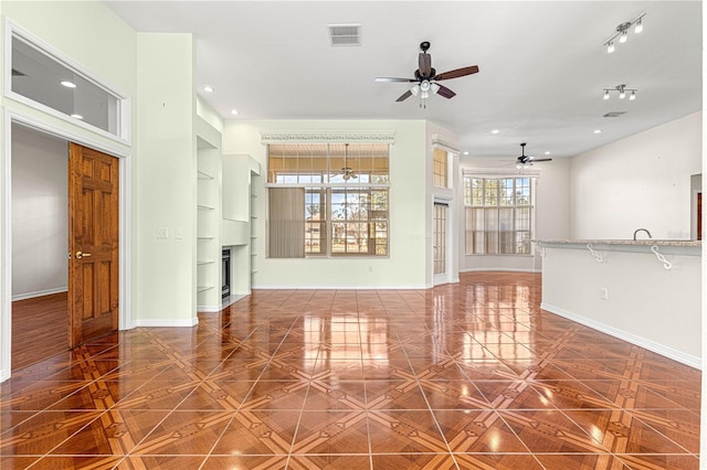 unfurnished living room featuring built in shelves, parquet flooring, and ceiling fan