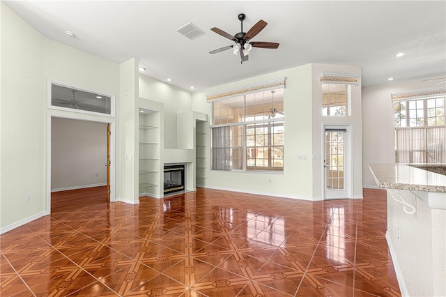 unfurnished living room featuring ceiling fan, dark parquet floors, and built in features