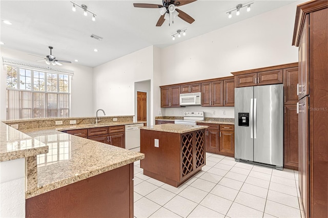 kitchen with sink, a center island, light tile patterned floors, kitchen peninsula, and white appliances