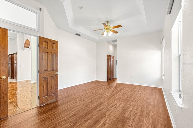 spare room with ceiling fan, wood-type flooring, and a tray ceiling