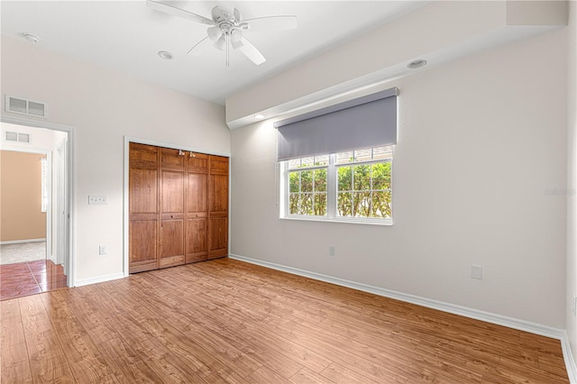 unfurnished bedroom with hardwood / wood-style flooring, ceiling fan, and a closet