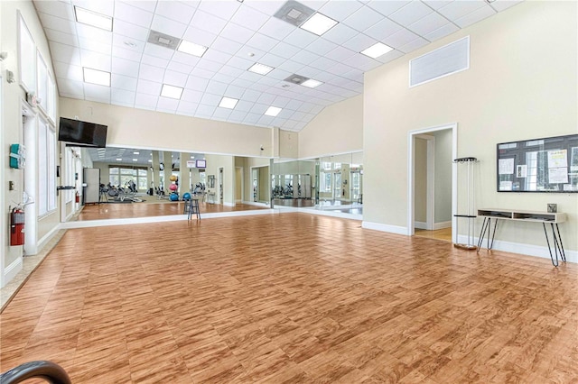 workout area featuring a towering ceiling and hardwood / wood-style floors