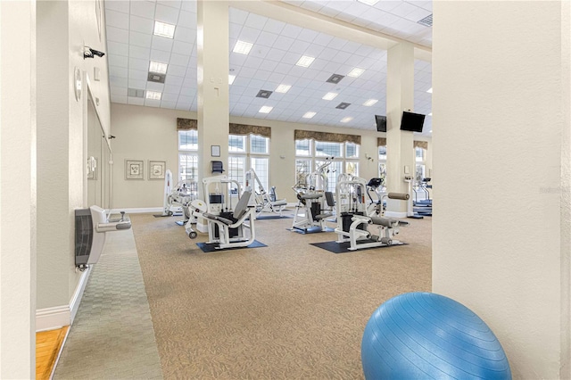 workout area with a towering ceiling and a paneled ceiling