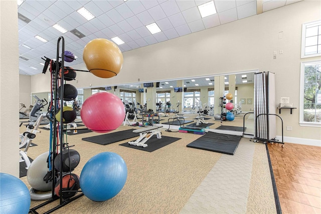 exercise room with a towering ceiling and a paneled ceiling