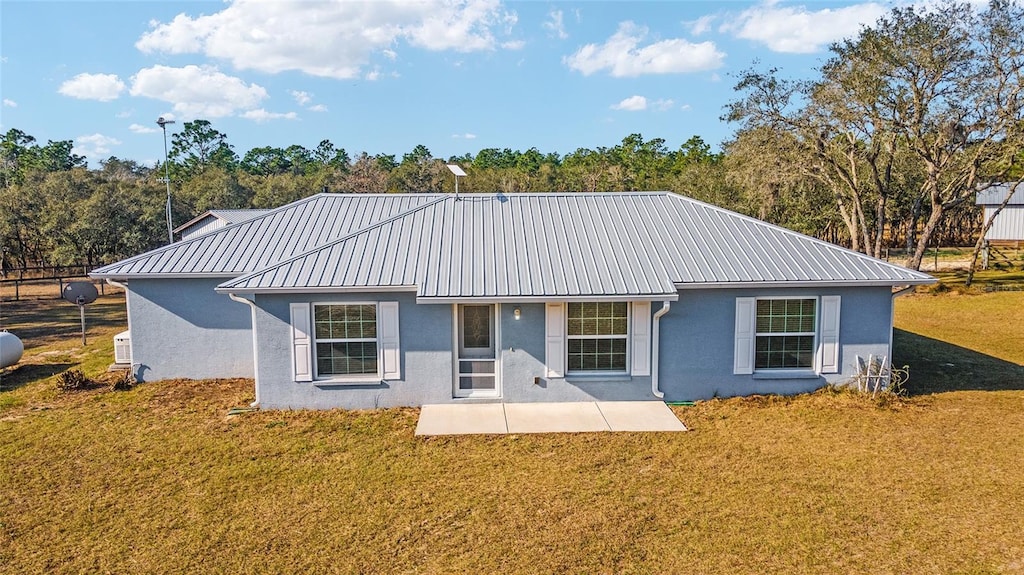 back of property with a patio area and a lawn