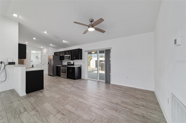 kitchen with lofted ceiling, ceiling fan, appliances with stainless steel finishes, light hardwood / wood-style floors, and kitchen peninsula