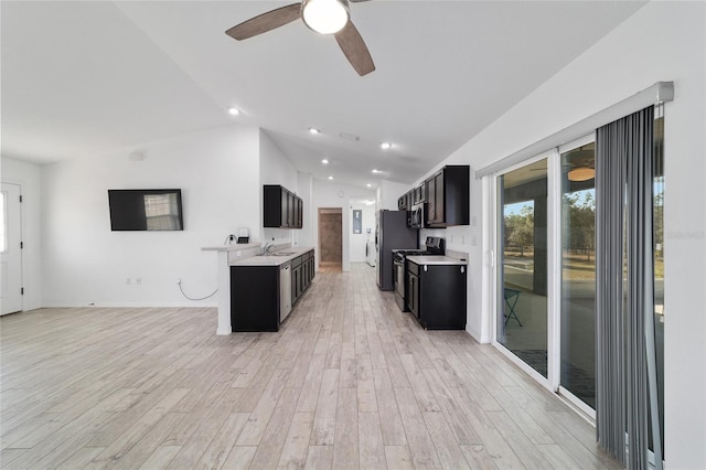 kitchen with a healthy amount of sunlight, appliances with stainless steel finishes, vaulted ceiling, and light wood-type flooring