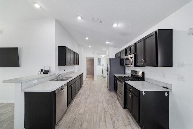 kitchen featuring lofted ceiling, sink, a kitchen bar, washing machine and clothes dryer, and stainless steel appliances