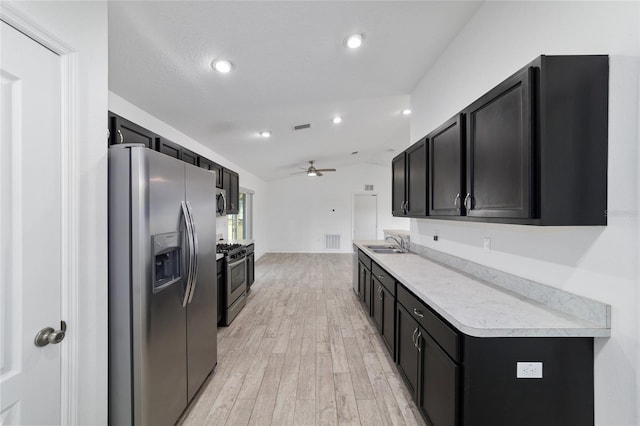 kitchen featuring sink, light hardwood / wood-style flooring, ceiling fan, appliances with stainless steel finishes, and vaulted ceiling