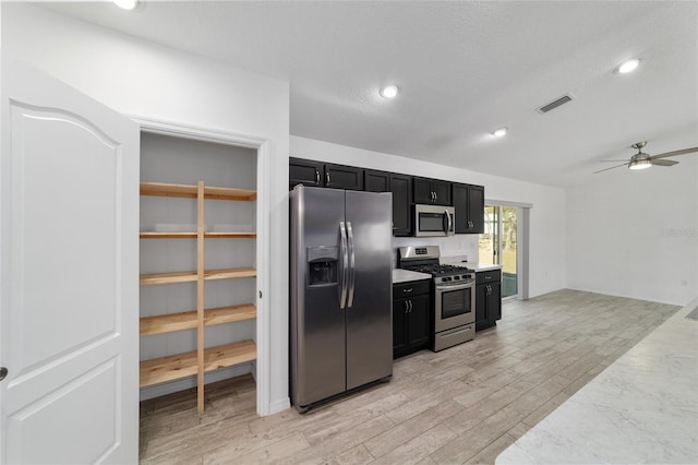 kitchen featuring lofted ceiling, light wood-type flooring, ceiling fan, stainless steel appliances, and a textured ceiling