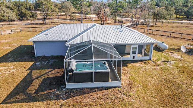 exterior space with a rural view, a lawn, a hot tub, and a sunroom