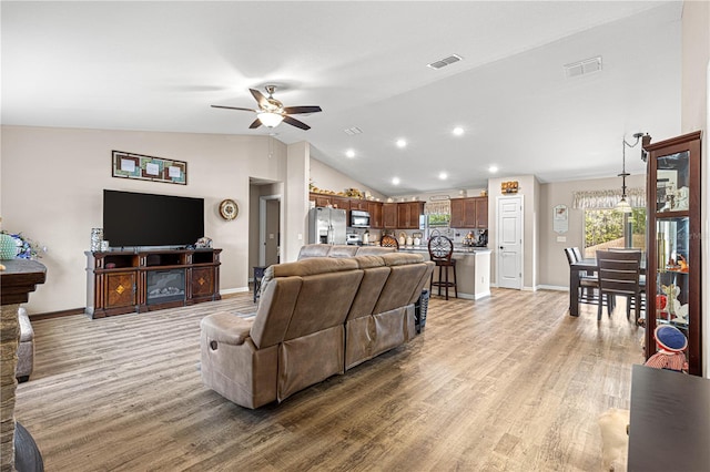 living room with lofted ceiling, light hardwood / wood-style floors, and ceiling fan