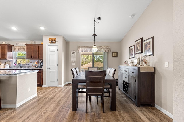 dining space with wood-type flooring and vaulted ceiling