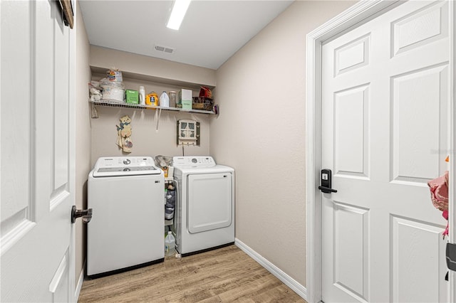 laundry room with washing machine and dryer and light hardwood / wood-style floors