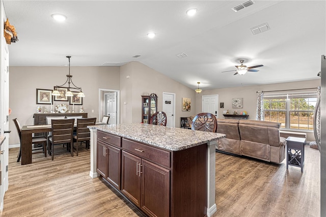 kitchen with light stone countertops, lofted ceiling, light wood-type flooring, and decorative light fixtures