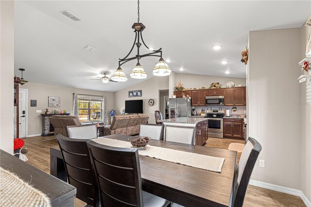 dining area with vaulted ceiling, ceiling fan, and light hardwood / wood-style flooring