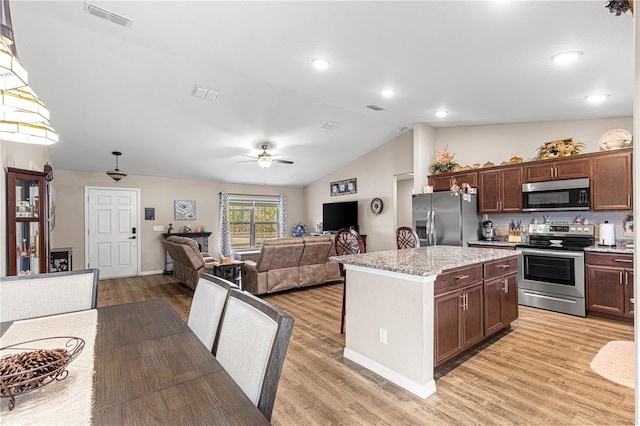 kitchen featuring appliances with stainless steel finishes, a center island, vaulted ceiling, and light hardwood / wood-style flooring