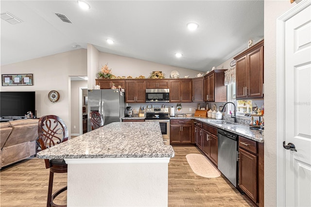 kitchen featuring appliances with stainless steel finishes, a kitchen bar, a center island, and sink