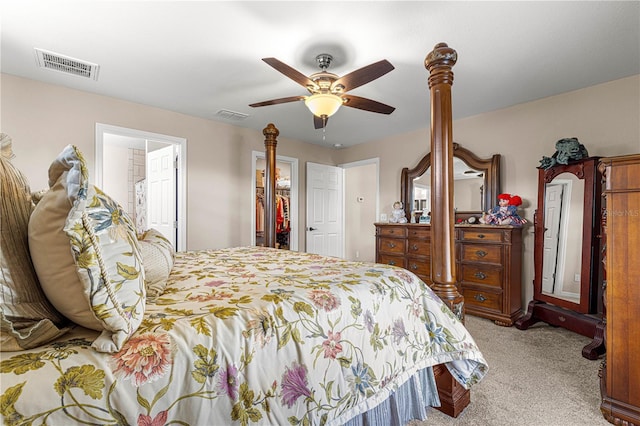 bedroom featuring ensuite bath, a walk in closet, light colored carpet, a closet, and ceiling fan