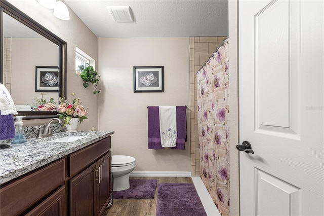 bathroom with walk in shower, toilet, a textured ceiling, vanity, and hardwood / wood-style flooring