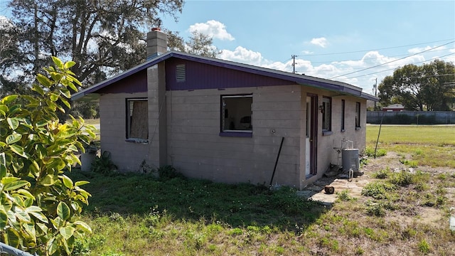 view of home's exterior with a chimney, fence, and cooling unit