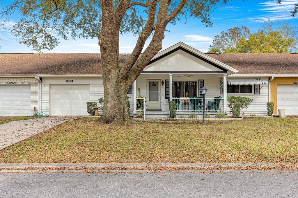 ranch-style house featuring a porch, a garage, and a front lawn