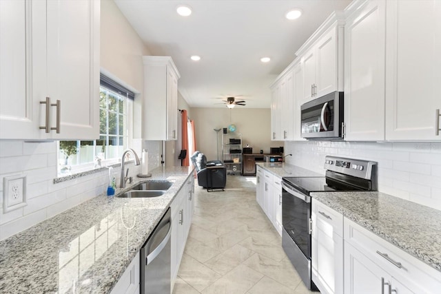 kitchen featuring sink, ceiling fan, appliances with stainless steel finishes, white cabinetry, and light stone counters