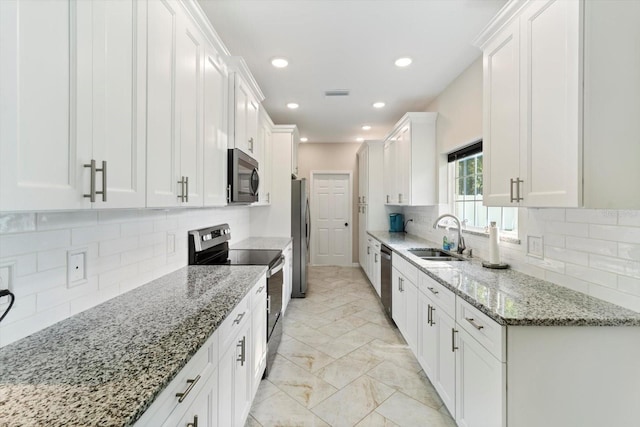 kitchen with light stone counters, sink, white cabinets, and appliances with stainless steel finishes