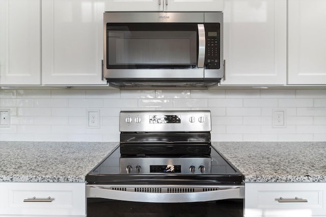 kitchen featuring light stone counters, backsplash, stainless steel appliances, and white cabinets