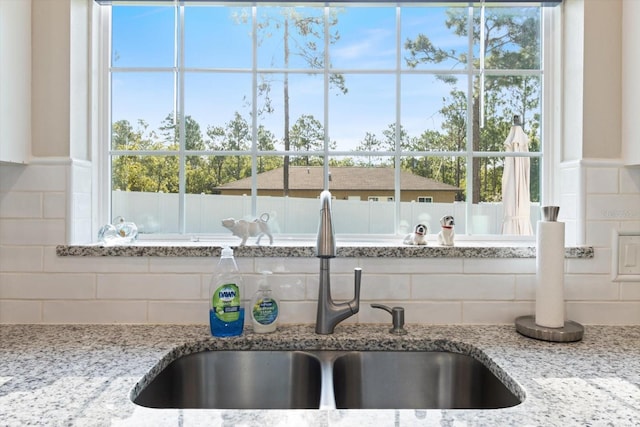 details with tasteful backsplash, light stone countertops, and sink