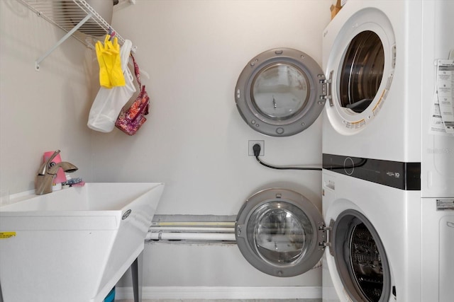 laundry area featuring stacked washing maching and dryer and sink