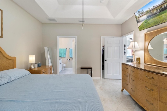 bedroom featuring ensuite bathroom and a tray ceiling