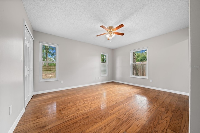 unfurnished room with ceiling fan, wood-type flooring, and a textured ceiling