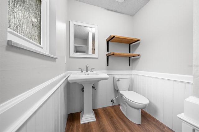 bathroom featuring hardwood / wood-style flooring, toilet, and a textured ceiling