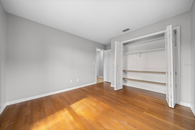 unfurnished bedroom featuring hardwood / wood-style floors and a closet