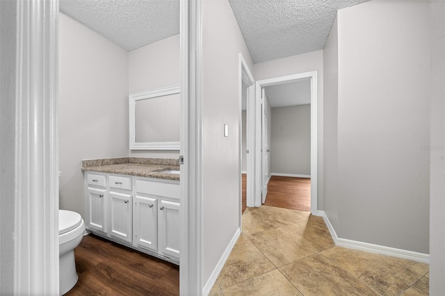 bathroom featuring vanity, tile patterned flooring, a textured ceiling, and toilet