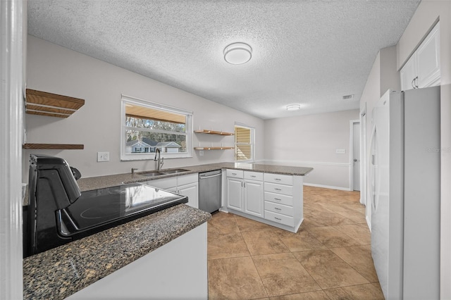 kitchen featuring sink, white cabinetry, stove, kitchen peninsula, and white fridge